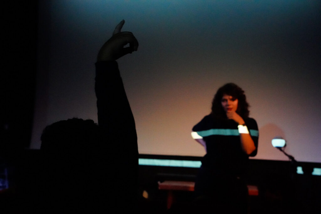 Photo d'un enfant à contre jour qui lève la main pendant que Samia semble se poser des questions