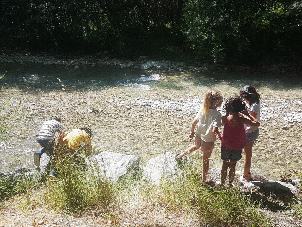Deux groupes d'enfants, casques sur les oreilles, enregistrent le son de la rivière en contrebas. Il fait beau. C'est l'été.