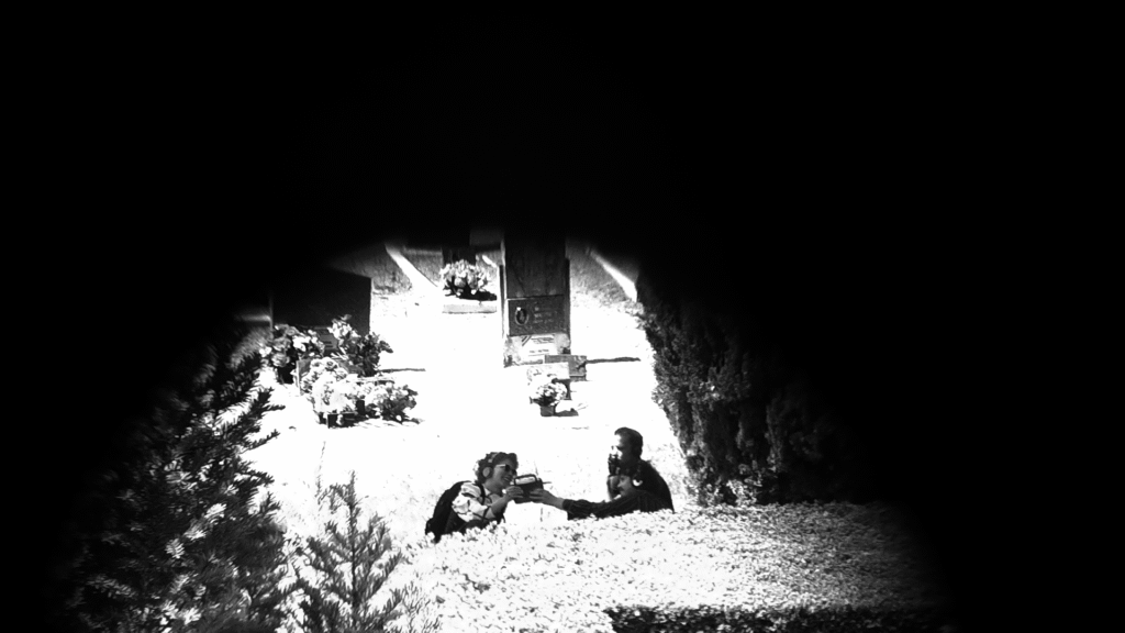 Un groupe d'amis assis par terre dans un cimetière, casque sur les oreilles, lève une radio vers le ciel en souriant.